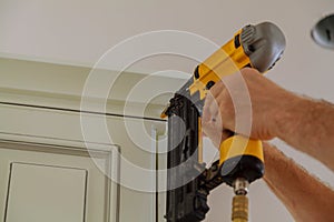 Carpenter brad using nail gun to Crown Moulding on kitchen cabinets framing trim,