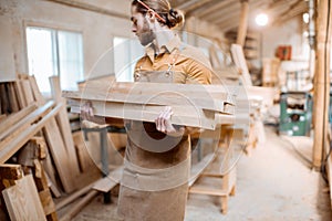 Carpenter carrying pine planks in the warehosue