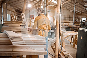 Carpenter carrying pine planks in the warehosue