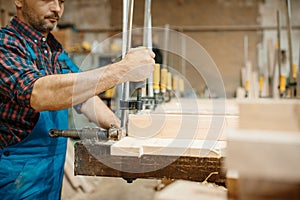 Carpenter clamps the board in a vise, woodworking