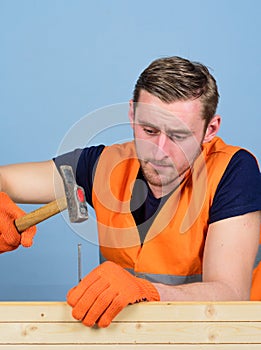 Carpenter concept. Carpenter, woodworker, builder on concentrated face hammering nail into wooden board. Man, handyman