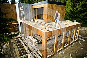 Carpenter constructing wooden frame house.