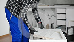 A carpenter with a corded jigsaw cutting a part of the wooden surface (board