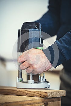 Carpenter or craftsman works with a router on a wooden panel