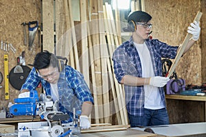 Carpenter cutting wood on circular saw. Two Young male carpenter working wood workshop