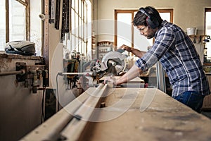 Carpenter cutting wood with a mitre saw in his workshop photo