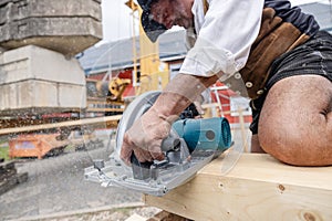 carpenter cutting wooden beam with electrical saw