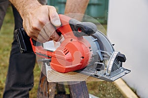 Carpenter cutting wooden plank hand held electric saw