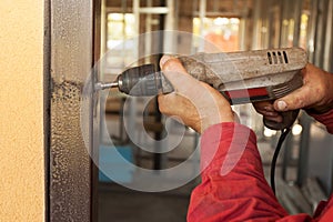 Carpenter at door installation with electric drill.