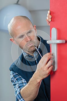 Carpenter with doorlock during lock process installation photo