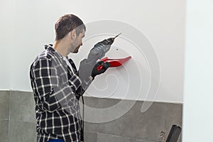 A carpenter drilling holes in the wall