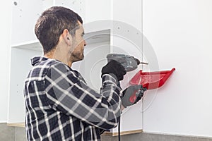 A carpenter drilling holes in the wall