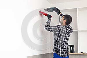 A carpenter drilling holes in the wall