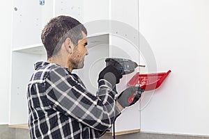 A carpenter drilling holes in the wall