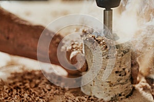 Carpenter drilling into a section of a branch of wood