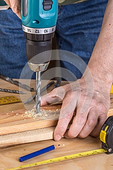 Carpenter drilling wood using portable drilling machine