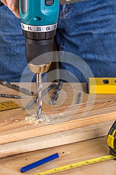 Carpenter drilling wood using portable drilling machine