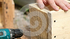 Carpenter drilling wood using portable drilling machine.