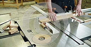 Carpenter engaged in his work. Wood cutting on the machine. Male hands close up