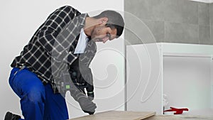 The carpenter finalizing the assembly of the kitchen shelf