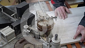 Carpenter glues part of the board on a special machine. Close-up.