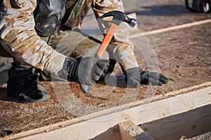 Carpenter hammering nail into OSB panel while building wooden frame house.