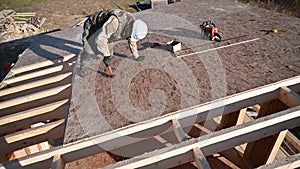 Carpenter hammering nail into OSB panel while building wooden frame house.