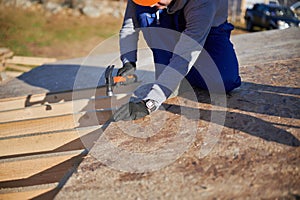 Carpenter hammering nail into OSB panel while building wooden frame house.