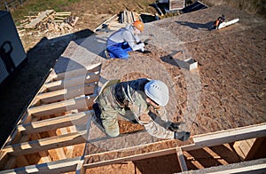 Carpenter hammering nail into OSB panel while building wooden frame house.