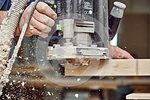 Carpenter with hand electric router machine at work. Milling process of acrylic kitchen countertop