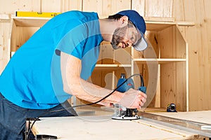 Carpenter with hand wood router machine at work. closeup of routing  slot into plank of pine woodworking construction tool concept