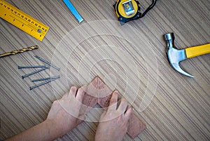 Carpenter hands measuring wood plank with a set collection of working hand tools