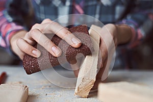 Carpenter hands polishing wooden planks with a sandpaper. Concept of DIY woodwork and furniture making