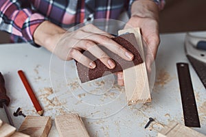 Carpenter hands polishing wooden planks with a sandpaper. Concept of DIY woodwork and furniture making