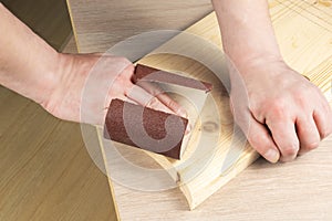 Carpenter hands polishing wooden planks with a sandpaper. Concept of DIY woodwork and furniture making