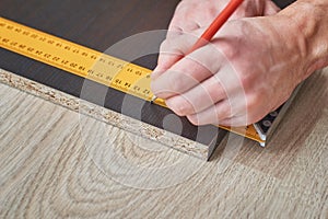Carpenter hands taking measurement of wooden plank, closeup