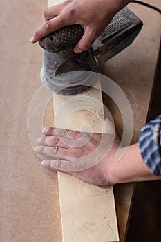 Carpenter hands Using Electric Sander. Carpenter sanding a wood