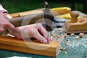 Carpenter hands using hammer hit the nail on wood. Woodwork concept