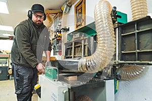 Carpenter hands using wood planer machine to plane wood in a carpentry workshop