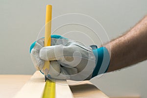 Carpenter handyman using pencil to mark the plank