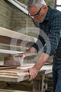 Carpenter hewing the wood and looking involved