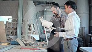 Carpenter and his boss discuss their job in a carpenter's workshop