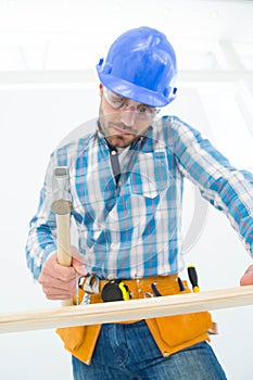 Carpenter hitting nail on wooden plank