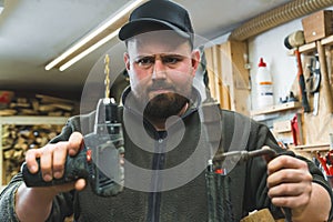 A carpenter holding an electrical drill machine and a hand drill comparing both