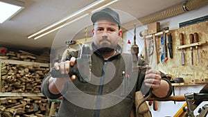 carpenter holding his drill and a brace in his repair shop, woodworking concept