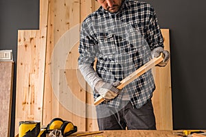 Carpenter is holding small pine plank in workshop