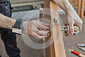 Carpenter installing door knob, close up human hend hold doorha