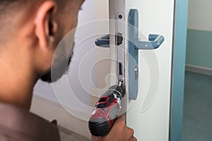 Carpenter Installing Door Lock With Wireless Screwdriver
