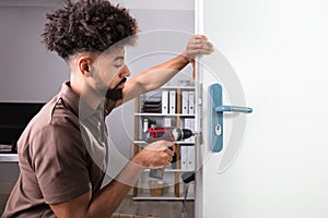 Carpenter Installing Door Lock With Wireless Screwdriver