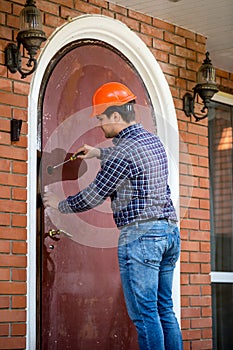 Carpenter installing lock at big metal door